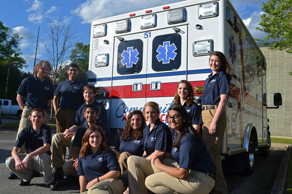 Team photo of Community Ambulance staff members at the back of a Community Ambulance vehicle