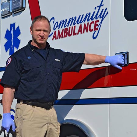 EMT standing next to Community Ambulance vehicle