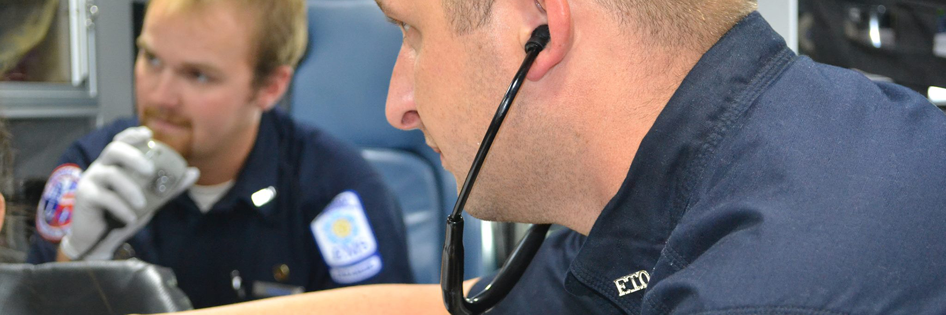 Two male EMTs in an ambulance assisting patient 